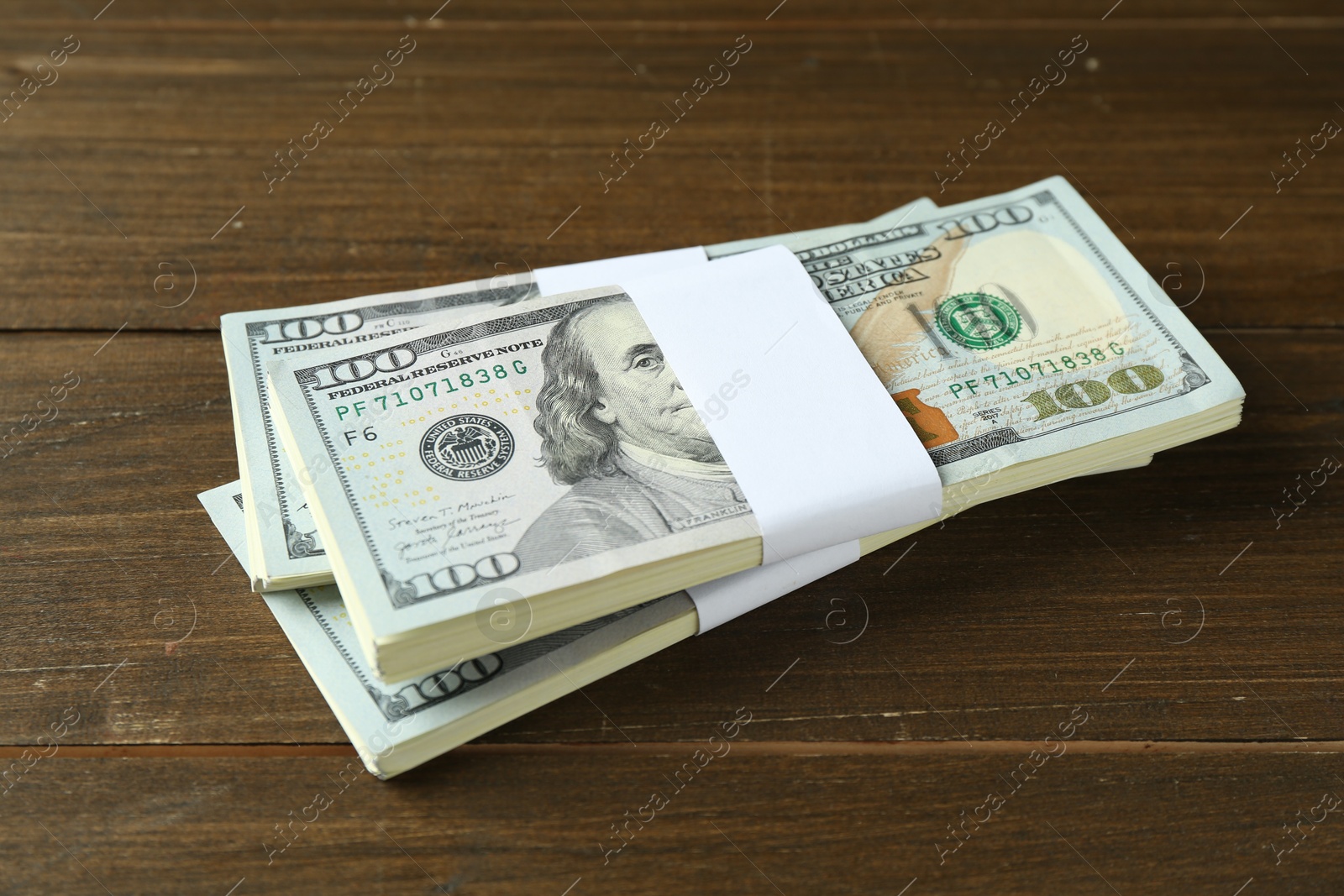 Photo of Bundles of dollar banknotes on wooden table