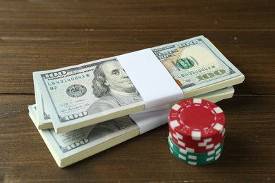 Bundles of dollar banknotes and casino chips on wooden table