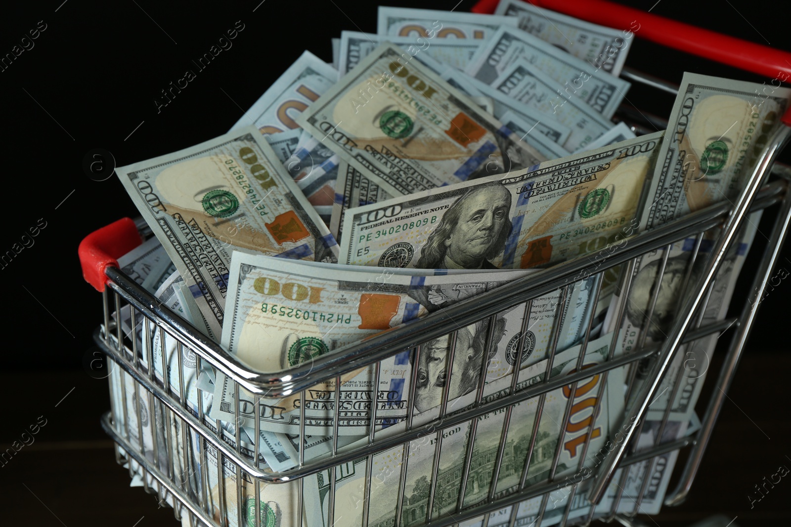 Photo of Many dollar banknotes in shopping cart on table, closeup