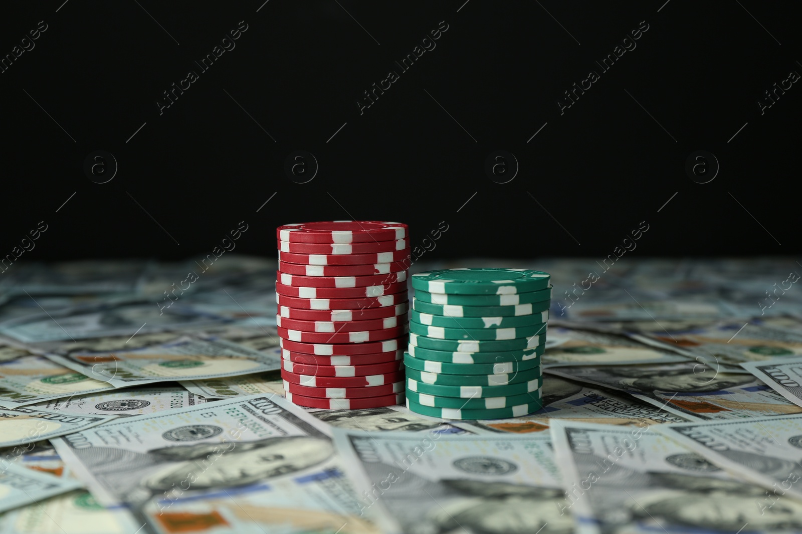 Photo of Many dollar banknotes and casino chips on black background