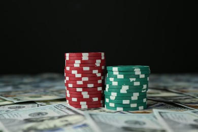 Photo of Many dollar banknotes and casino chips on black background