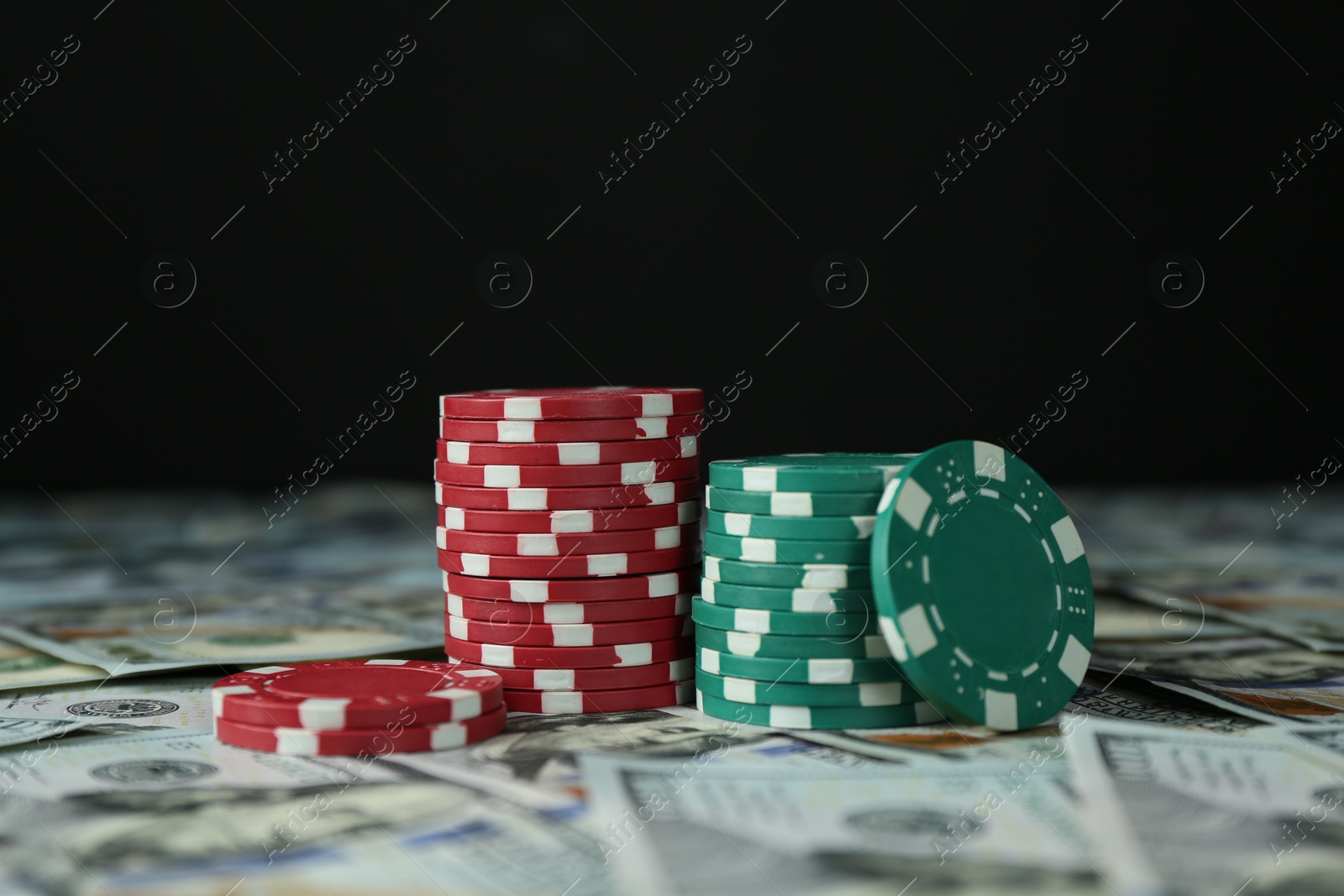 Photo of Many dollar banknotes and casino chips on black background