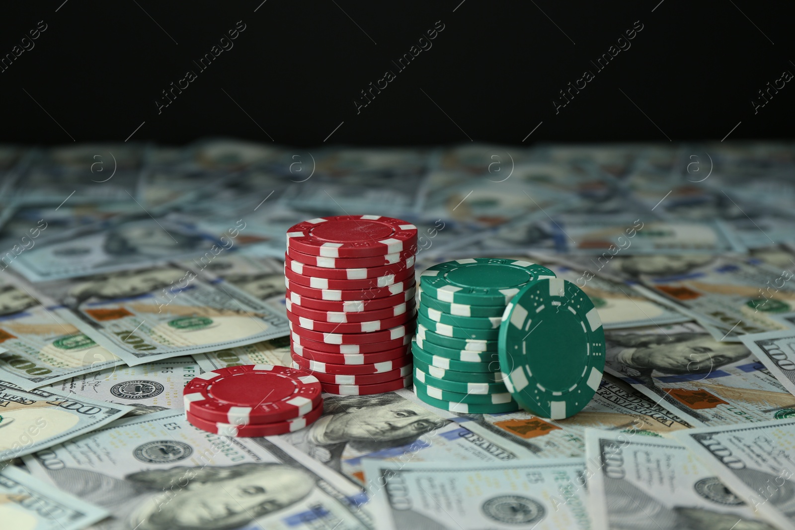 Photo of Many dollar banknotes and casino chips on black background