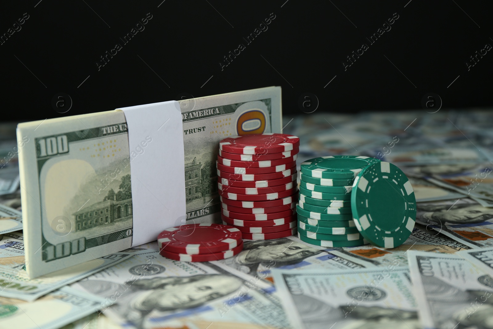 Photo of Many dollar banknotes and casino chips on black background