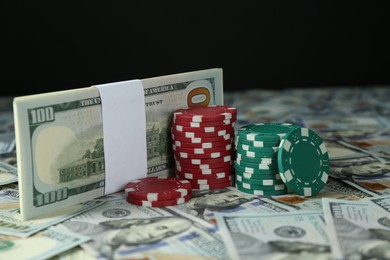 Photo of Many dollar banknotes and casino chips on black background