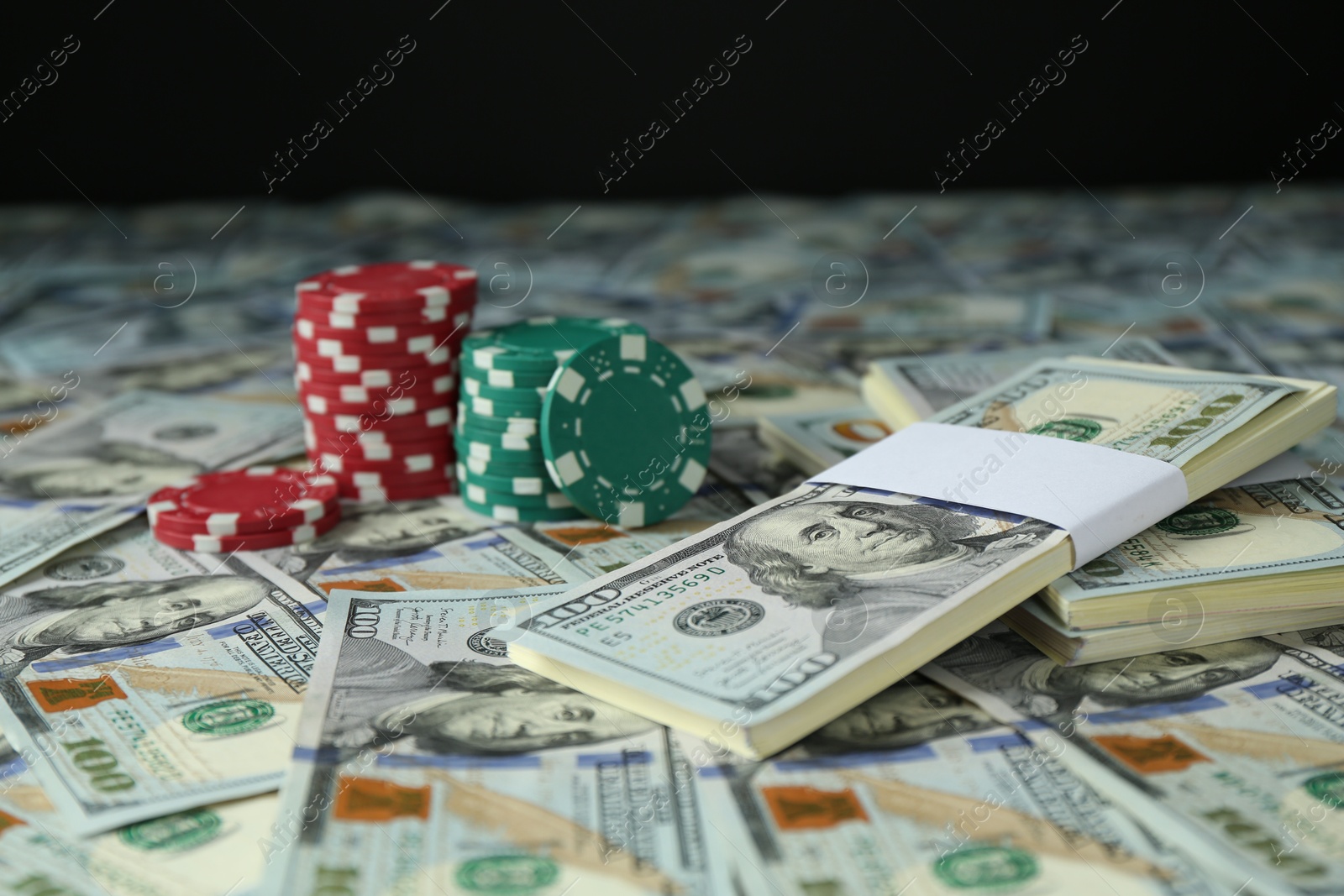 Photo of Many dollar banknotes and casino chips on black background, closeup