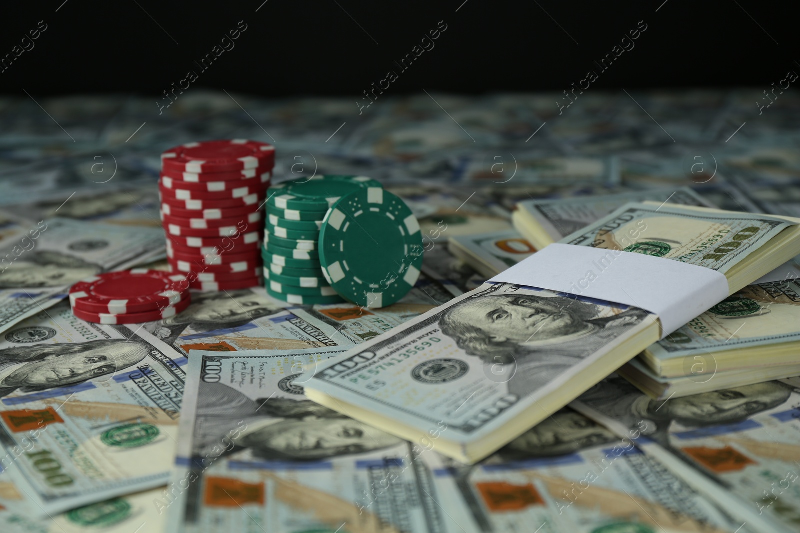 Photo of Many dollar banknotes and casino chips on black background, closeup