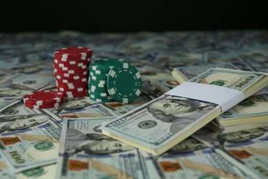 Many dollar banknotes and casino chips on black background, closeup