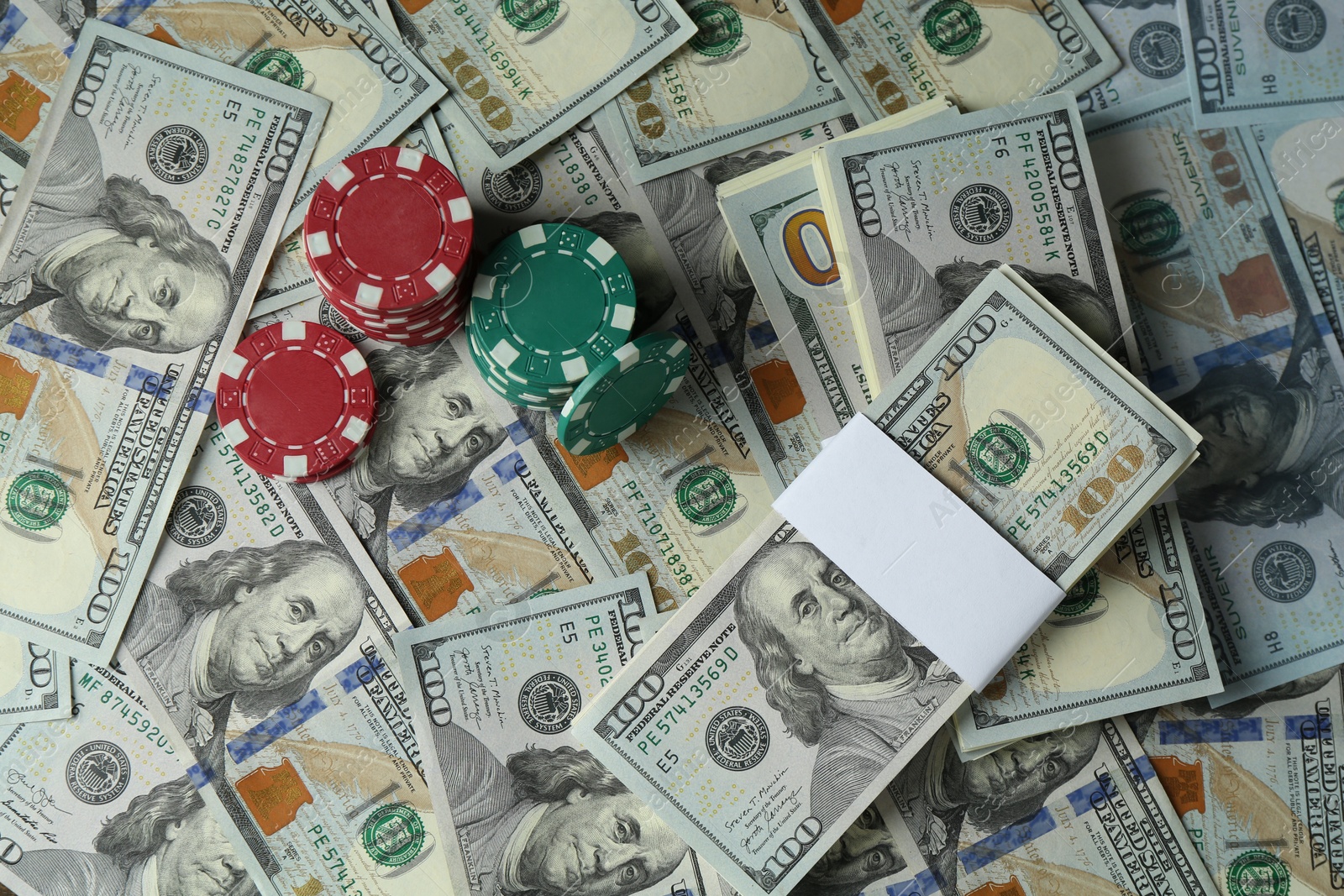 Photo of Many dollar banknotes and casino chips as background, top view