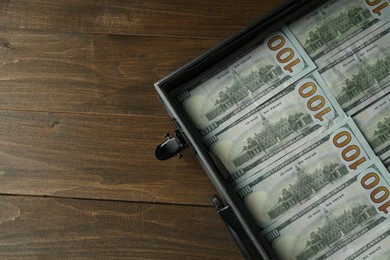 Metal case full of dollar banknotes on wooden table, top view. Space for text