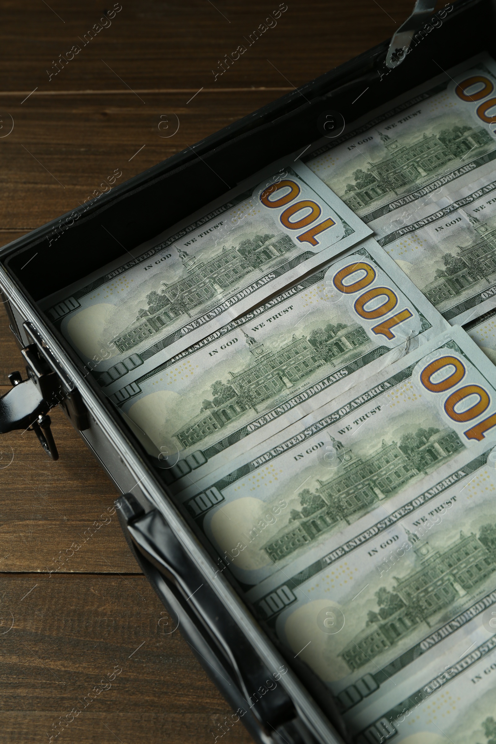 Photo of Metal case full of dollar banknotes on wooden table