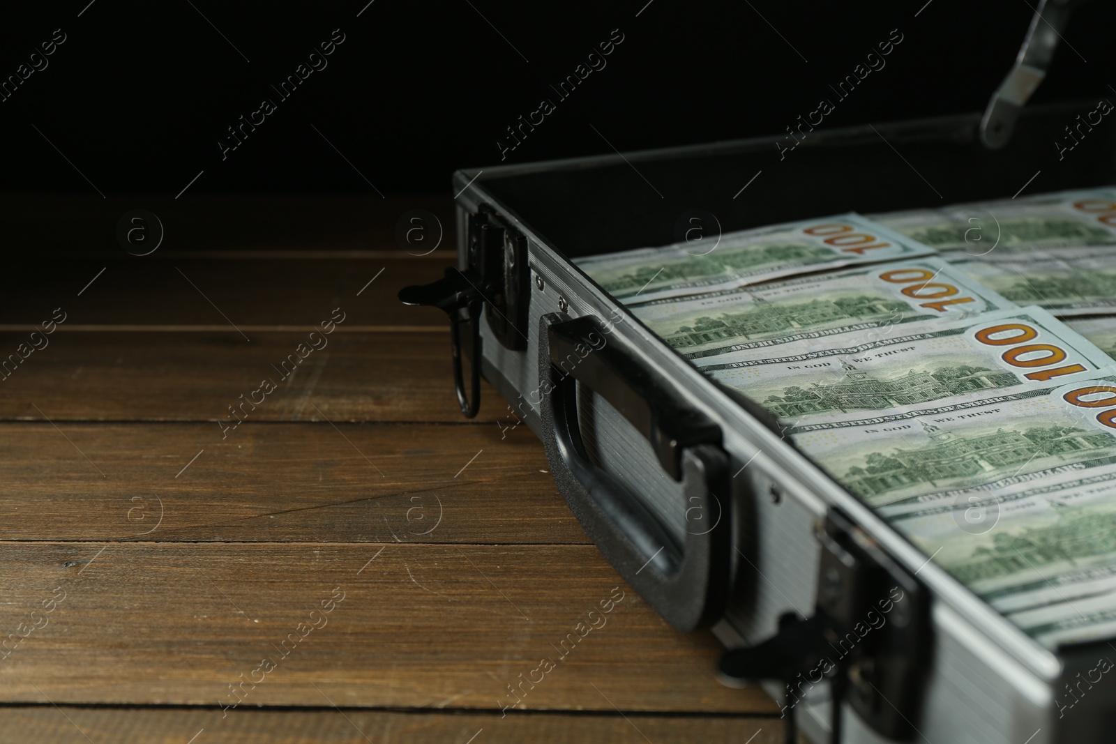 Photo of Metal case full of dollar banknotes on wooden table, closeup. Space for text