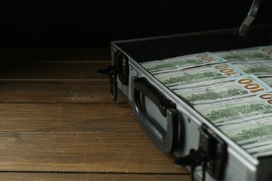 Metal case full of dollar banknotes on wooden table, closeup. Space for text