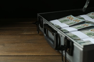 Photo of Metal case full of dollar banknotes on wooden table, closeup. Space for text