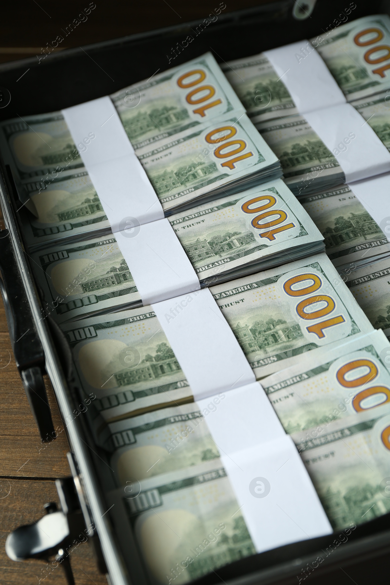 Photo of Metal case full of dollar banknotes on wooden table, closeup