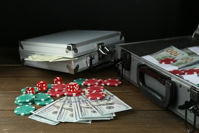 Photo of Metal cases full of dollar banknotes and casino chips on wooden table