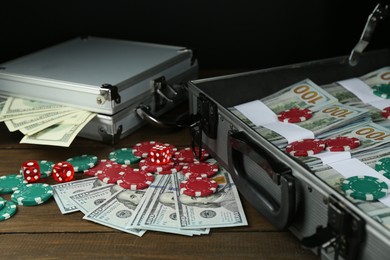 Photo of Metal cases full of dollar banknotes and casino chips on wooden table