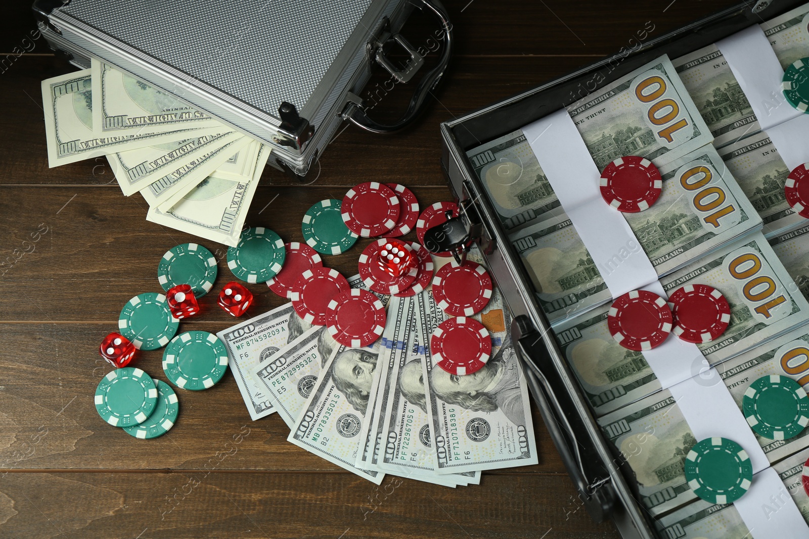 Photo of Metal cases full of dollar banknotes and casino chips on wooden table