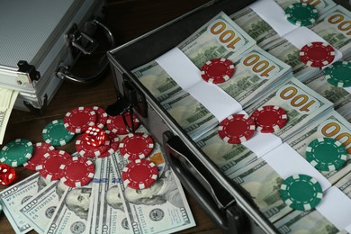 Metal cases full of dollar banknotes and casino chips on wooden table