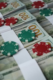 Many dollar banknotes and casino chips as background, closeup