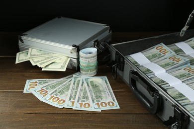 Photo of Metal cases full with dollar banknotes on wooden table