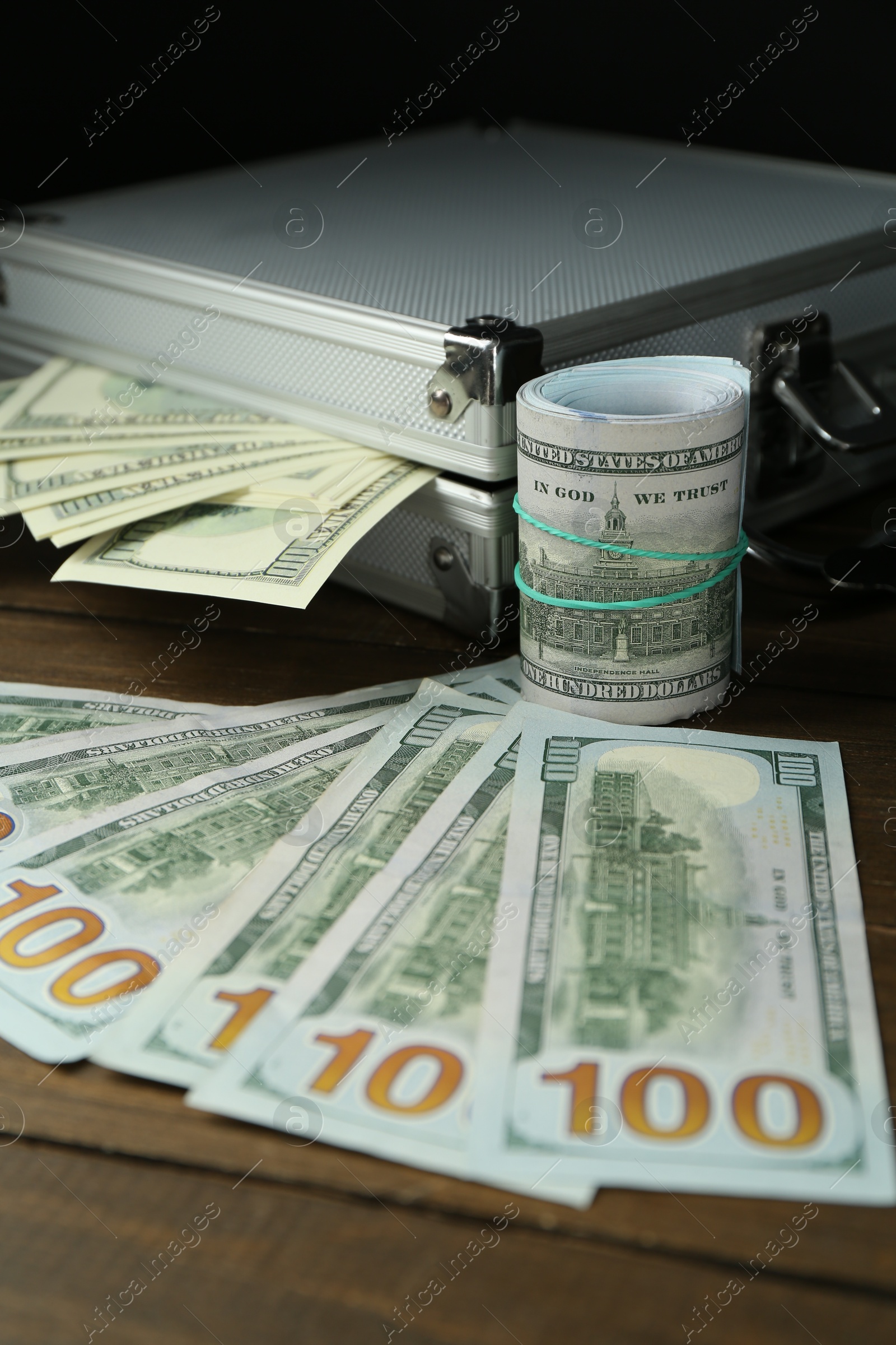 Photo of Metal cases full with dollar banknotes on wooden table, closeup