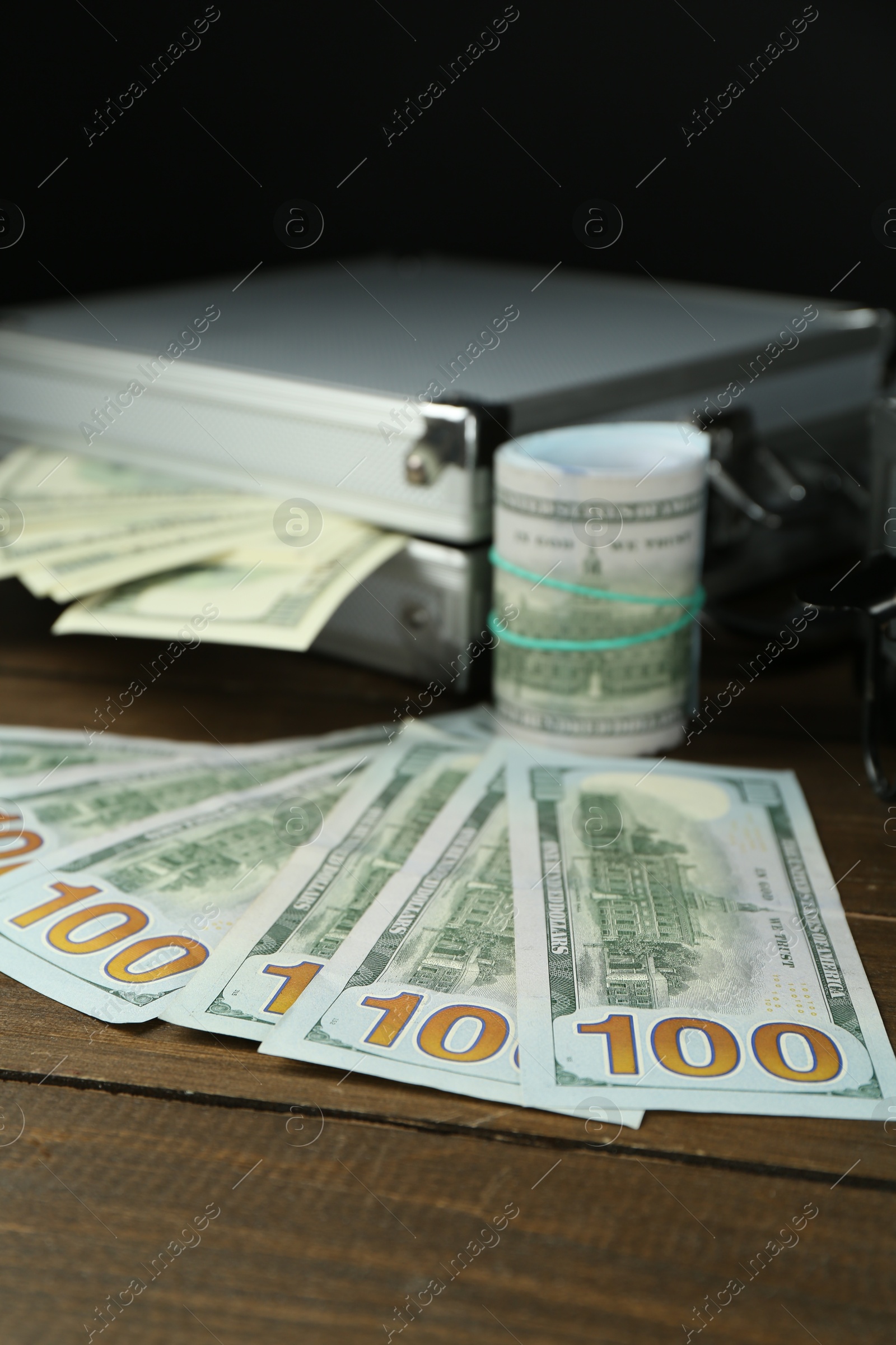 Photo of Metal cases full with dollar banknotes on wooden table, closeup