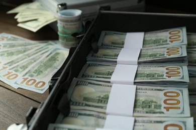 Metal case full of dollar banknotes on wooden table, closeup