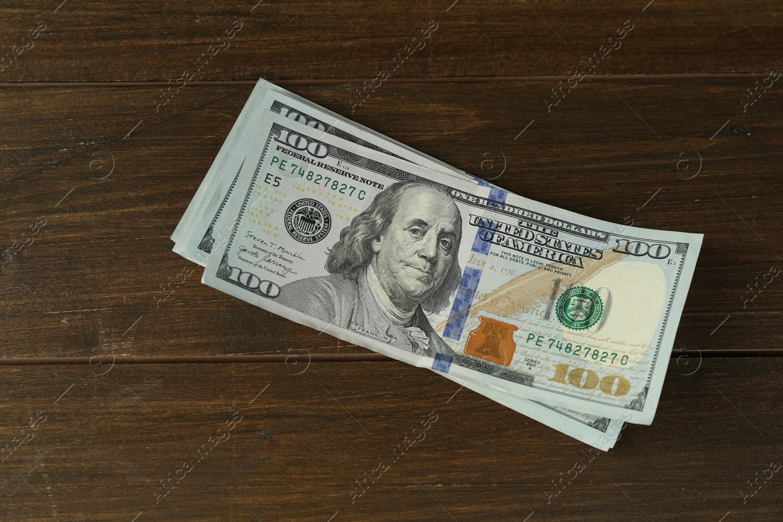 Photo of Many dollar banknotes on wooden table, top view