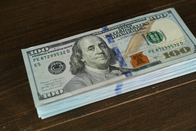 Photo of Stack of dollar banknotes on wooden table, closeup