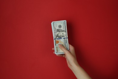 Photo of Woman with dollar banknotes on red background, closeup