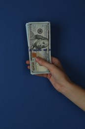 Woman with dollar banknotes on blue background, closeup