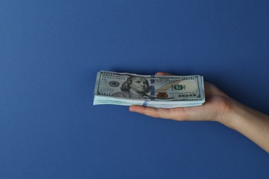 Photo of Woman with dollar banknotes on blue background, closeup. Space for text