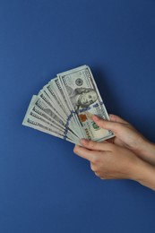 Woman with dollar banknotes on blue background, closeup