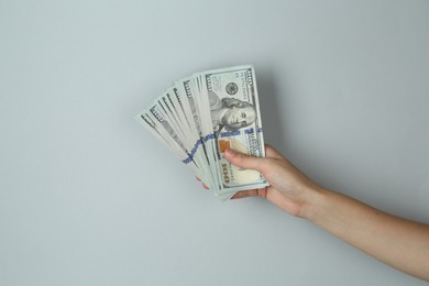 Woman with dollar banknotes on light grey background, closeup