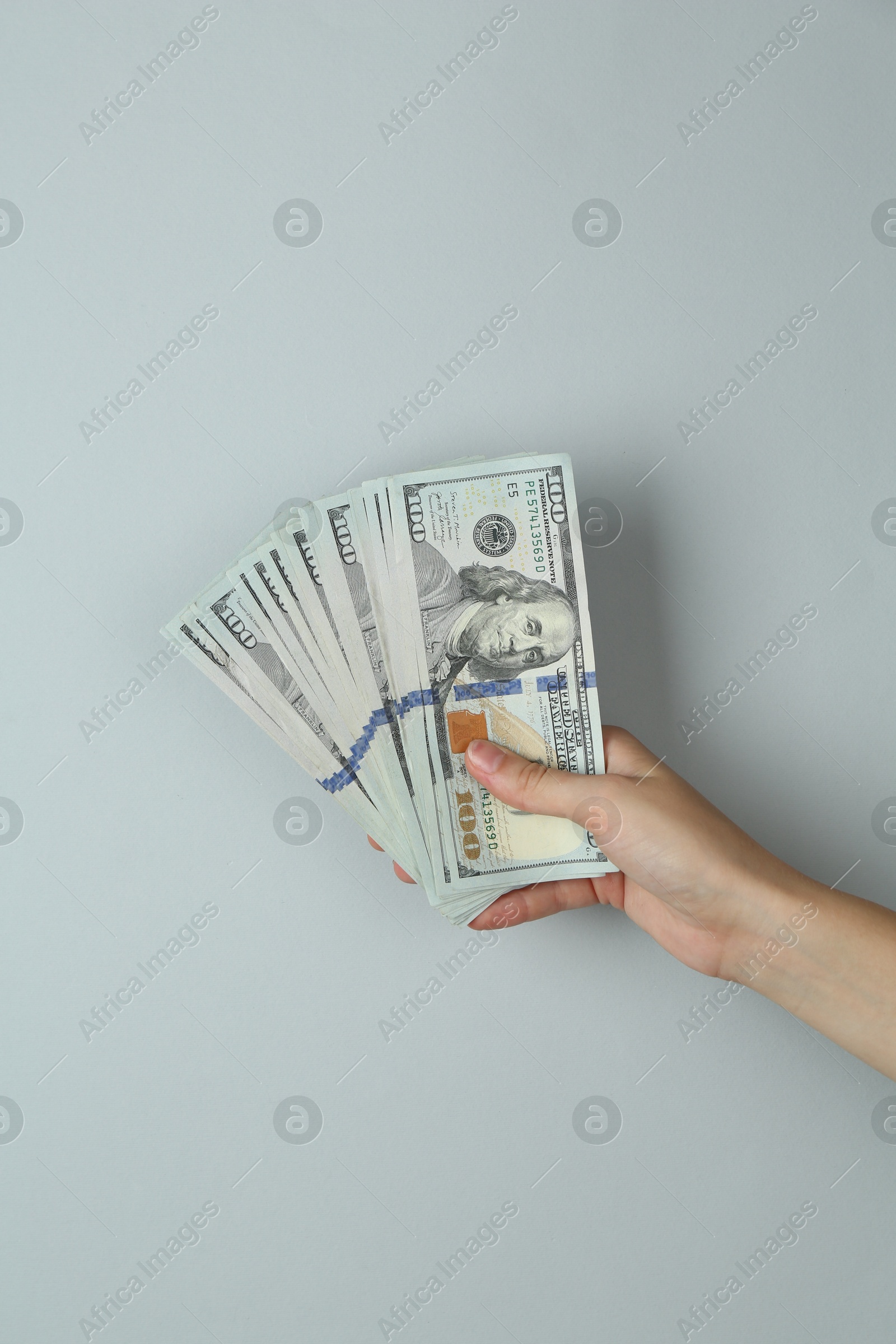 Photo of Woman with dollar banknotes on light grey background, closeup