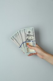 Woman with dollar banknotes on light grey background, closeup