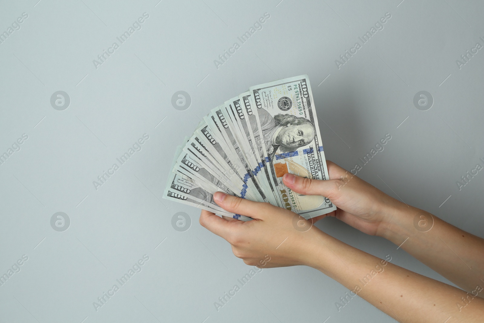 Photo of Woman with dollar banknotes on light grey background, closeup. Space for text