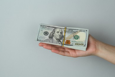 Woman with dollar banknotes on light grey background, closeup