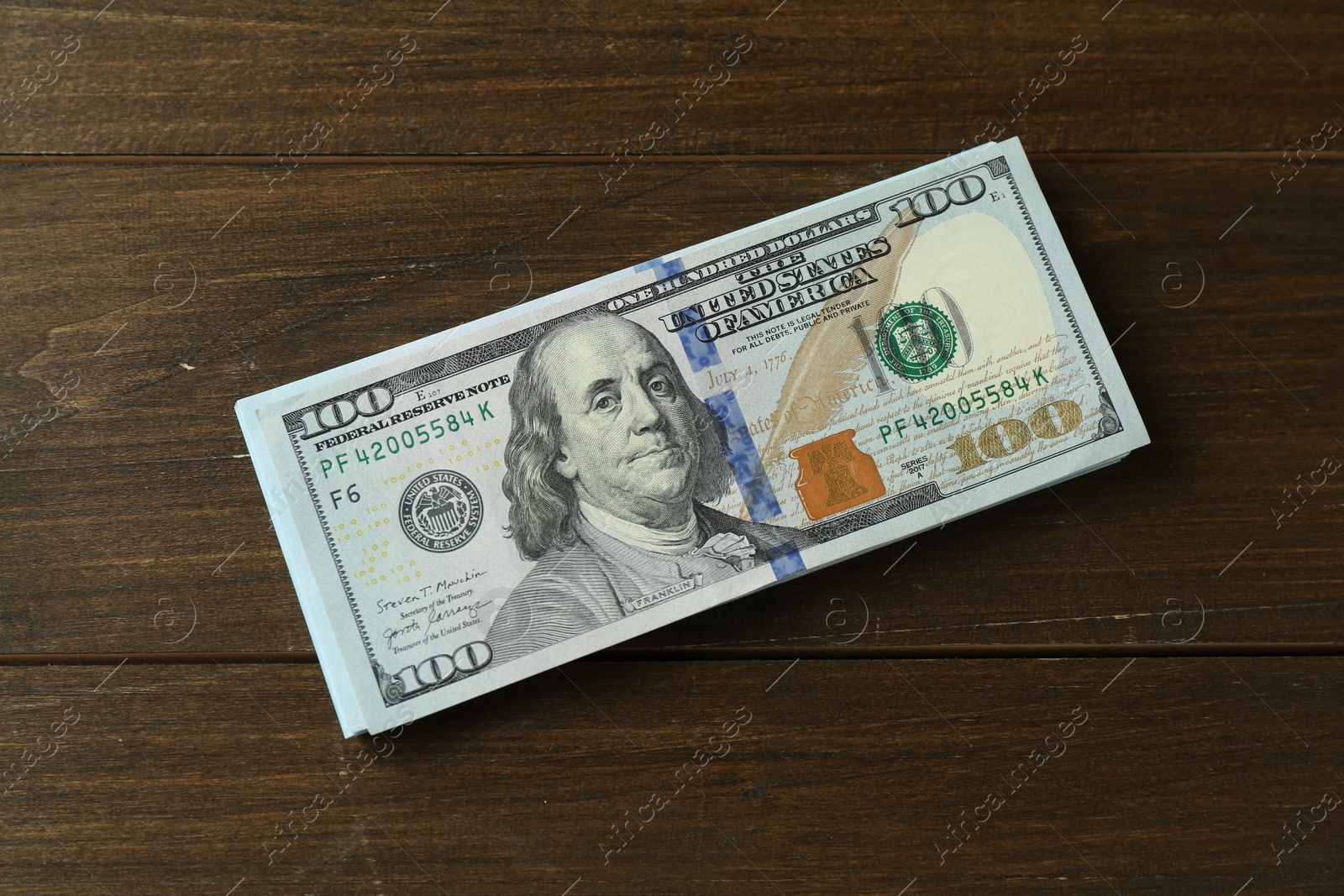 Photo of Stack of dollar banknotes on wooden table, top view