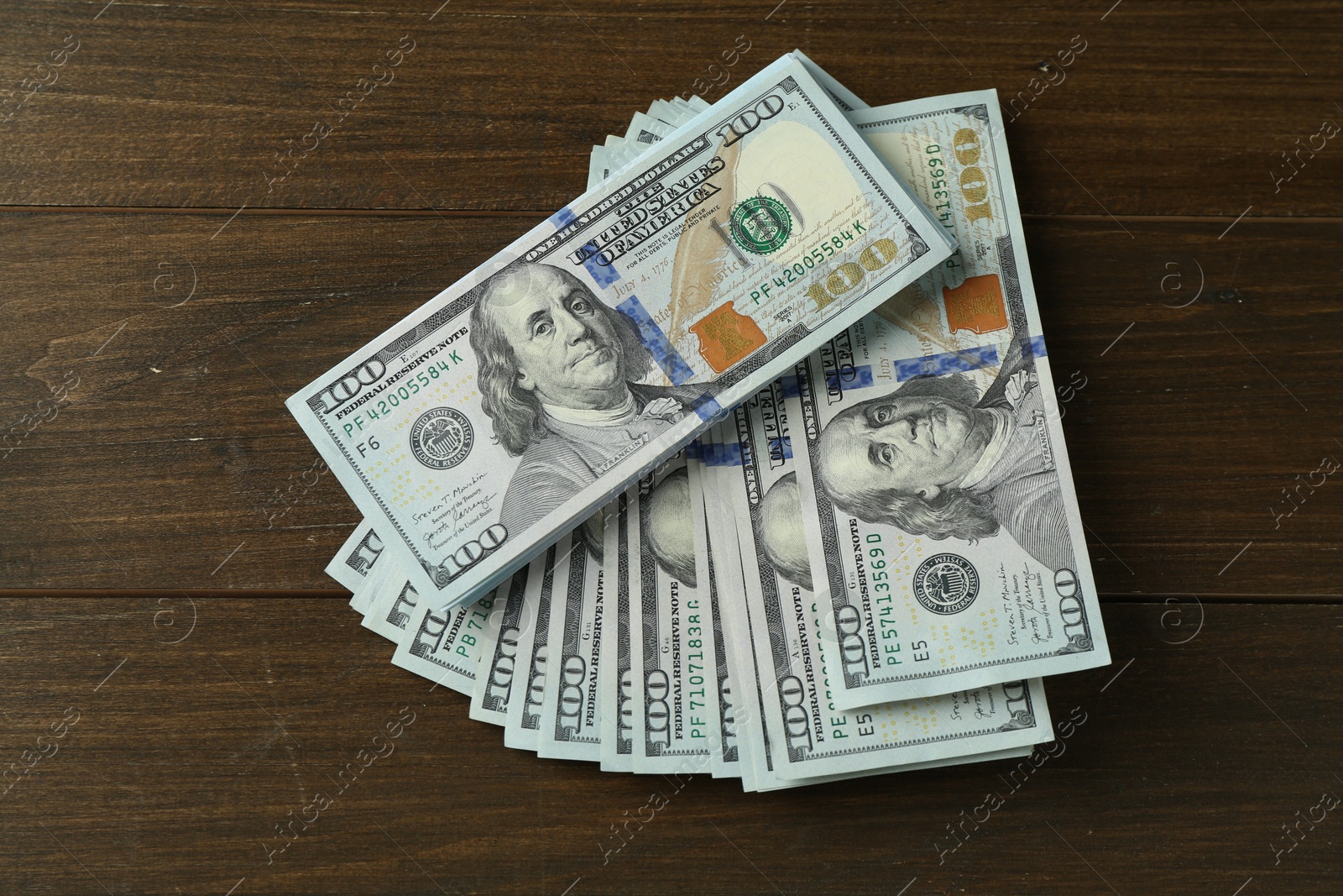 Photo of Many dollar banknotes on wooden table, top view