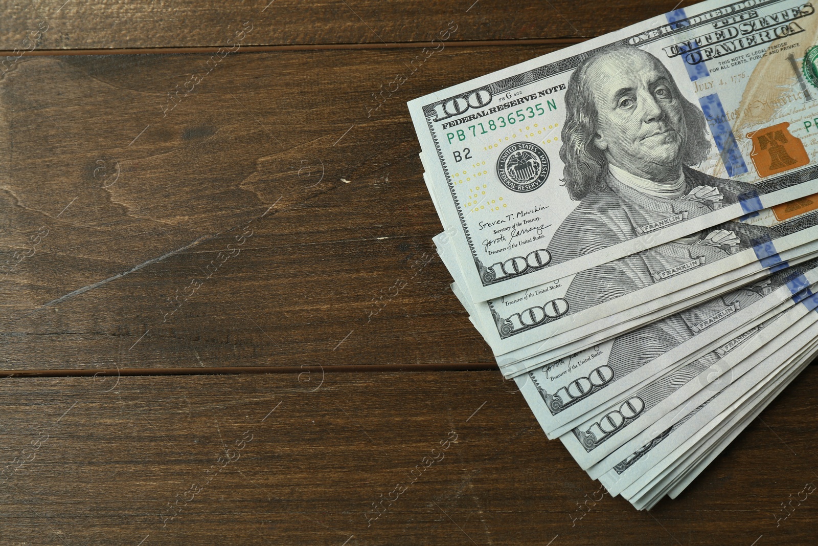 Photo of Many dollar banknotes on wooden table, top view. Space for text