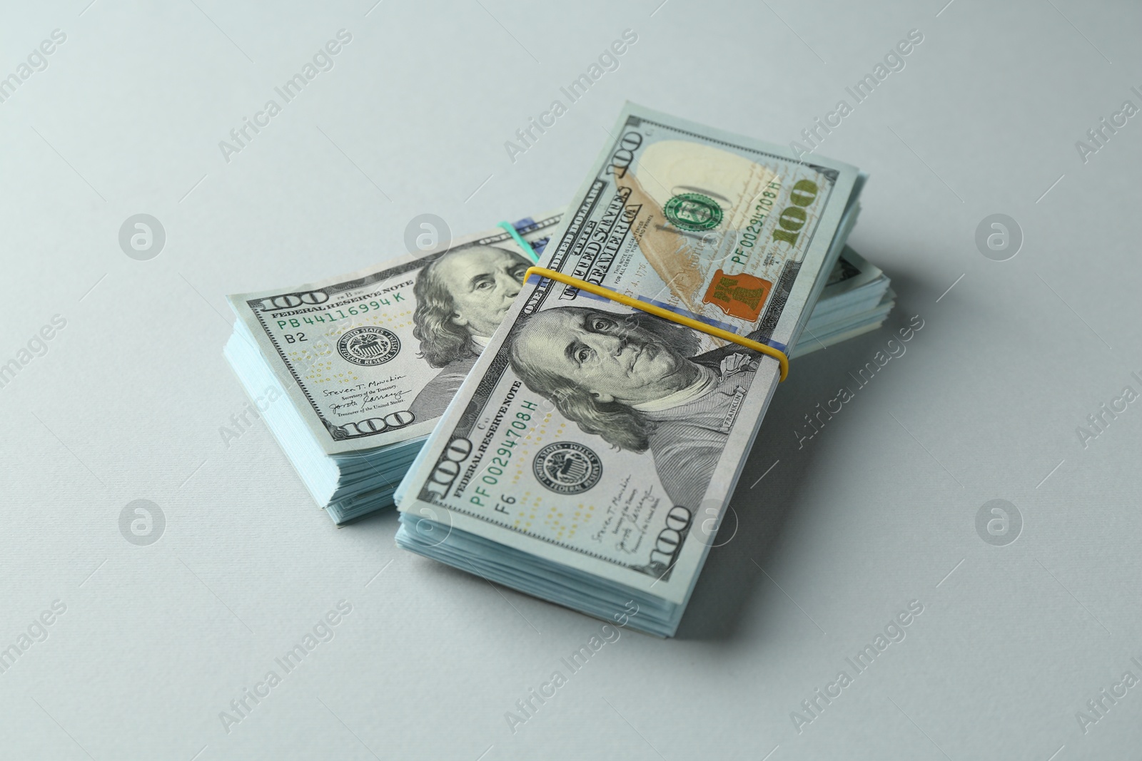 Photo of Bundles of dollar banknotes on light grey background