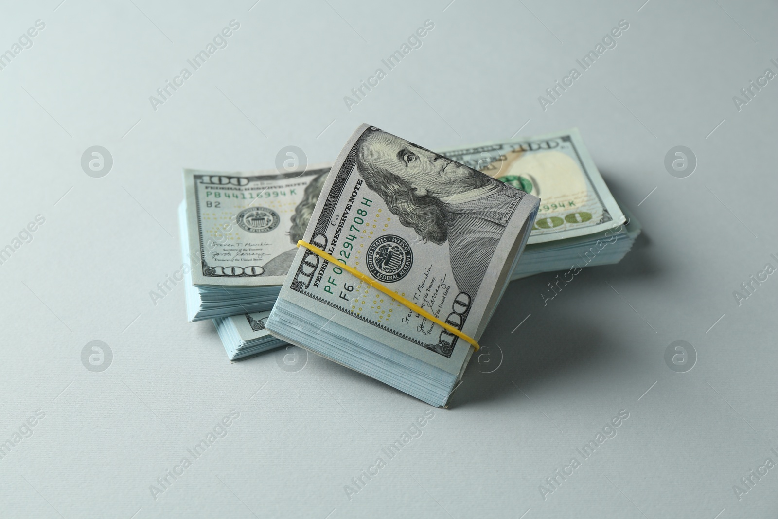 Photo of Bundles of dollar banknotes on light grey background