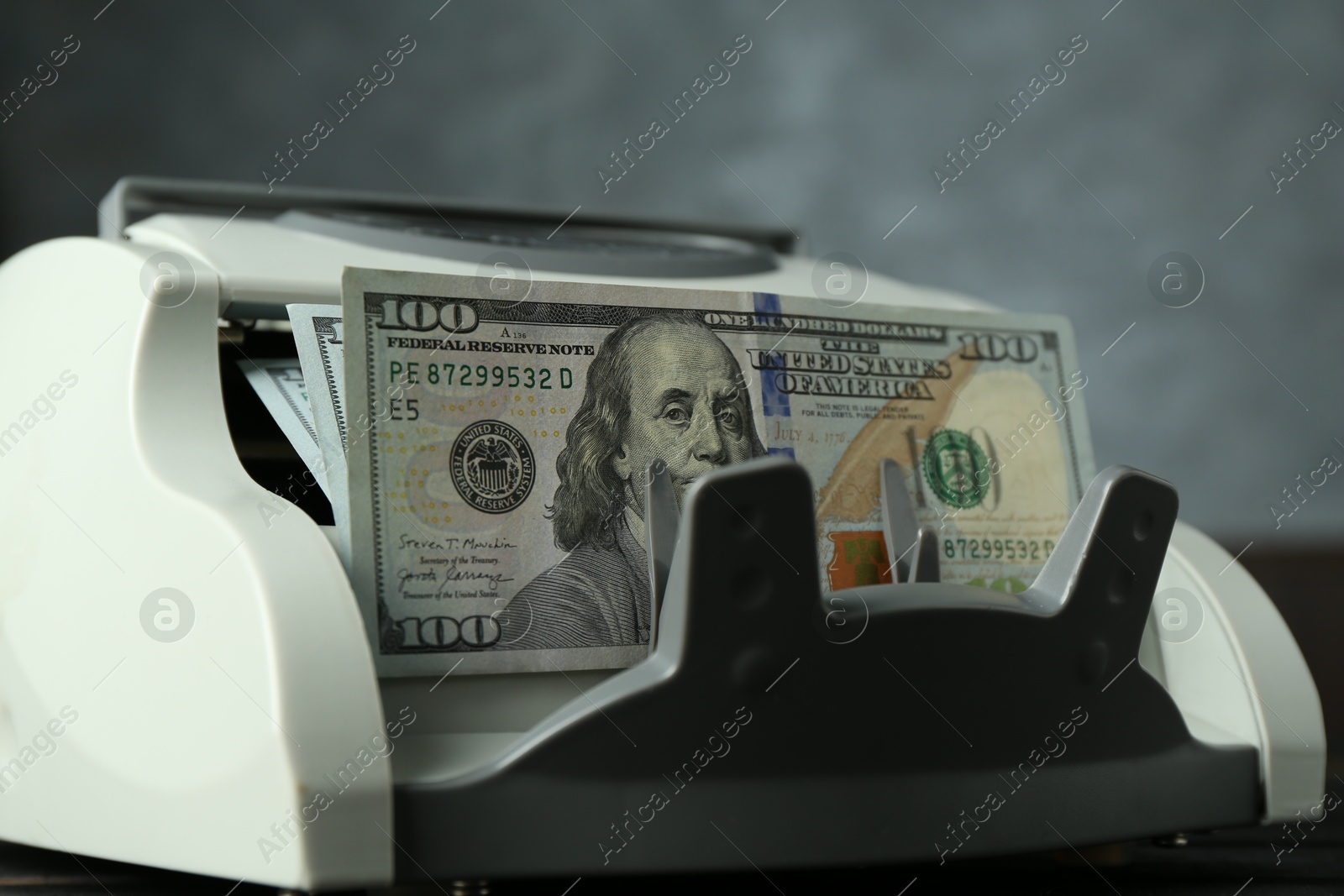 Photo of Money counter machine with dollar banknotes on table, closeup