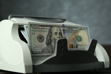 Money counter machine with dollar banknotes on table, closeup