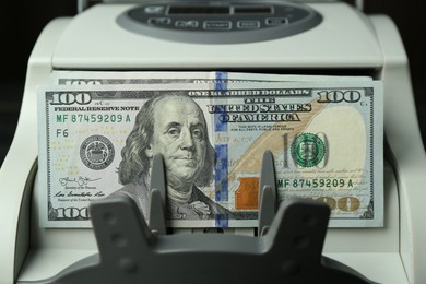 Photo of Money counter machine with dollar banknotes, closeup