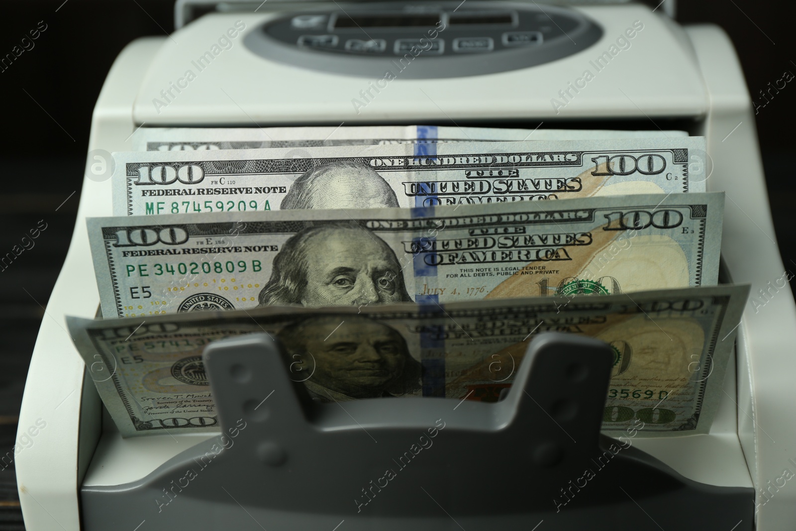 Photo of Money counter machine with dollar banknotes, closeup