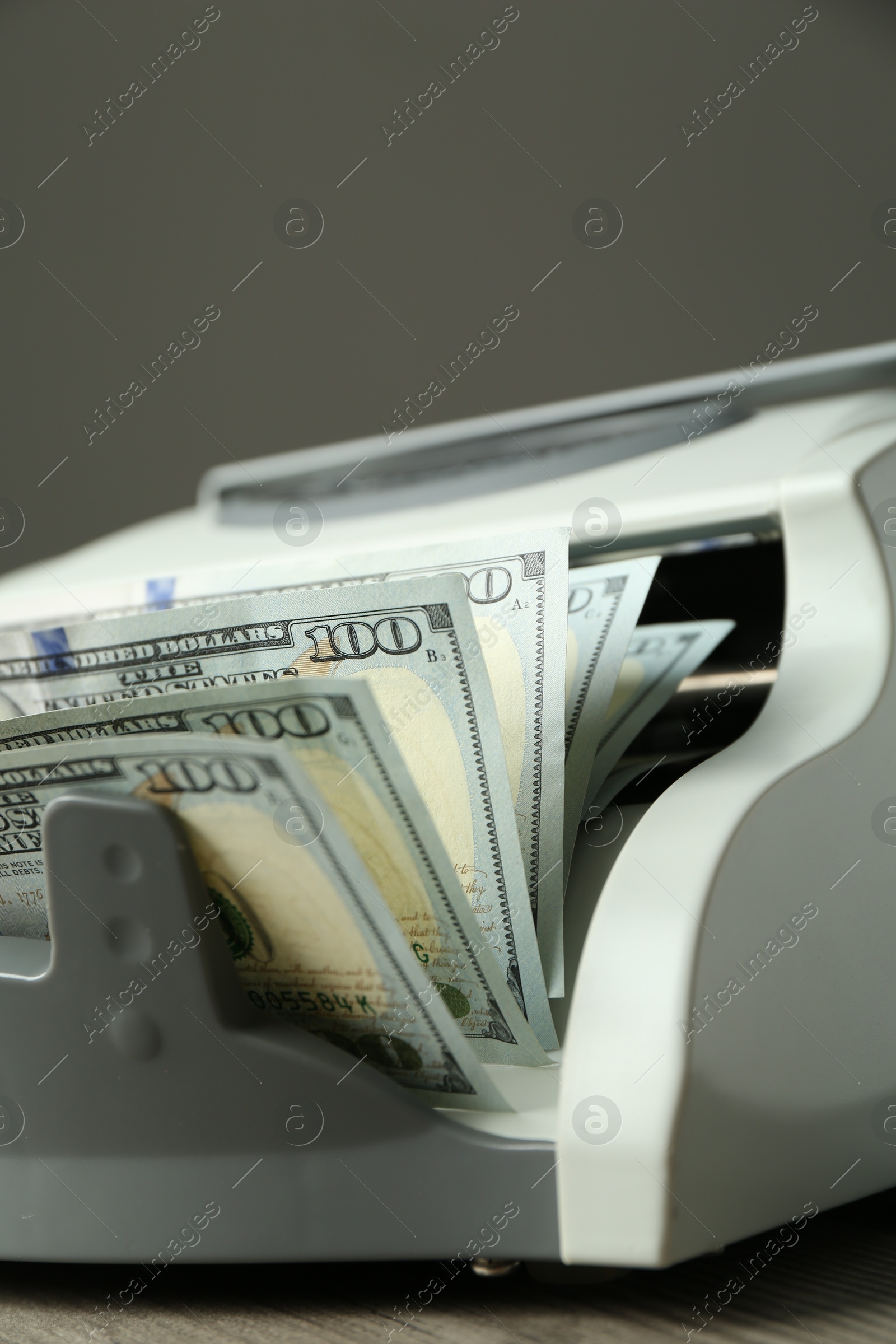 Photo of Money counter machine with dollar banknotes on table, closeup