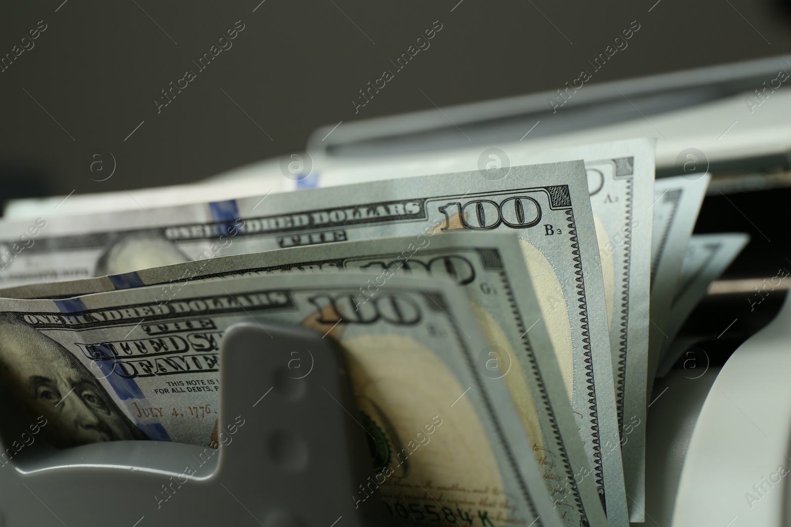 Photo of Money counter machine with dollar banknotes on grey background, closeup